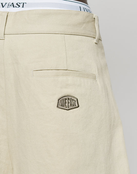Close-up of LFDY Twill Shorts by LIVE FAST DIE YOUNG, showcasing a stitched LIVE FAST patch on the back pocket and the waistband of white underwear with LIVE FAST text peeking above.