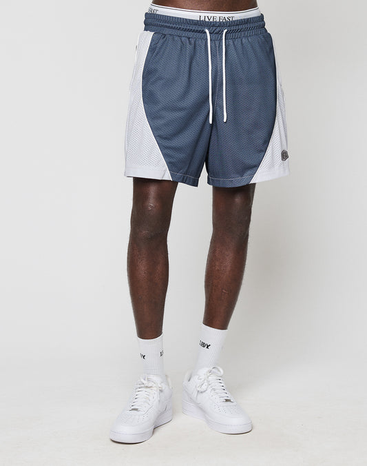 A person stands against a plain white background wearing LIVE FAST DIE YOUNG LFDY Piping Mesh Shorts in blue and white with a regular fit, elastic waistband, drawstring, and mesh side panels. Only the lower body is visible; socks and sneakers are white.