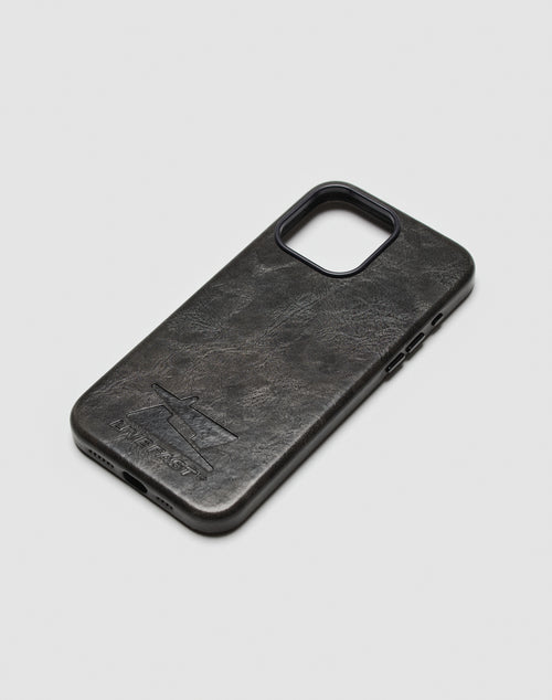 A black Live Fast Phone Case by LIVE FAST DIE YOUNG lies on a white surface, featuring an engraved airplane and the embossed FLIGHT TEST logo near the bottom corner.