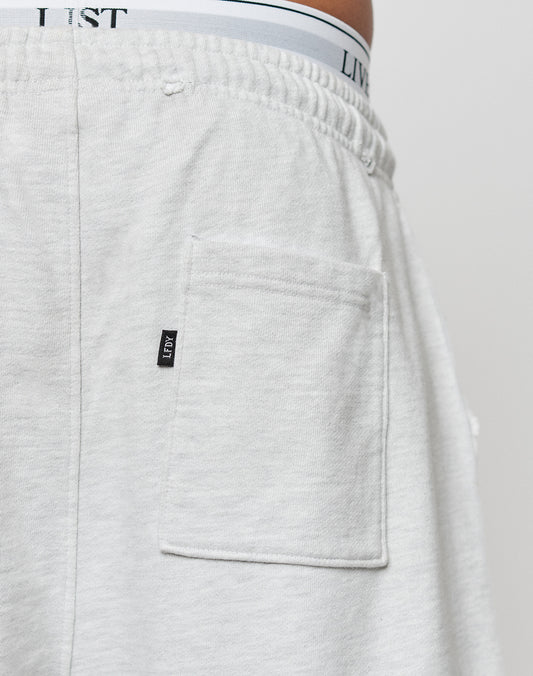 Close-up of the back pocket of light gray DY Rivet Shorts by LIVE FAST DIE YOUNG, featuring a black LIST tag on the pocket seam and white 100% Baumwolle underwear with LIST branding visible above the waistband.