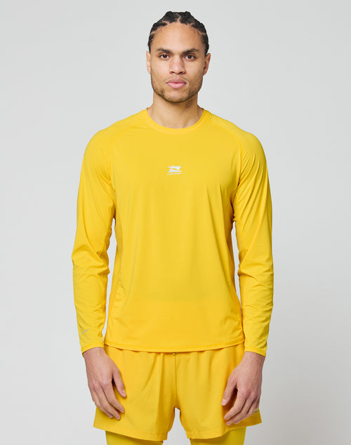 A person with braided hair stands against a plain light gray background, wearing the LIVE FAST DIE YOUNG Live Fast Performance Longsleeve in yellow and matching shorts, looking straight ahead with a neutral expression.