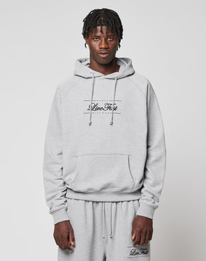 A young man with short braids wears a light gray LFDY Embroidery Hooded by LIVE FAST DIE YOUNG, paired with matching sweatpants. Both pieces feature "Live Fast" and he stands against a plain white background, looking at the camera.