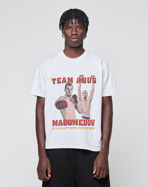 A man wearing the LIVE FAST DIE YOUNG Abus Magomedov Tee, a regular fit white cotton shirt with front and back prints: two male fighters, bold red TEAM ABUS MAGOMEDOV text, and "If you know, you know" at the bottom.