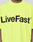 A person is seen in the Basic OS Livefast Tee by LIVE FAST DIE YOUNG, featuring an oversized fit and bold "LiveFast™" black front print on bright yellow 100% cotton. The person's face is not shown.