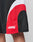 A close-up of a persons leg wearing LIVE FAST DIE YOUNG Basic Trackshorts in black polyester with red and white curved panels, logo print, and Live Fast Die Young phrase in white near the hem.