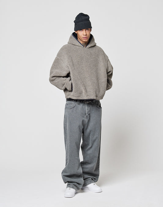 A person wearing the gray LFDY Teddy Hooded by LIVE FAST DIE YOUNG, baggy gray oversize jeans, a black beanie, and white sneakers stands against a plain white background with hands in pockets.