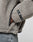 A close-up of a person wearing the LIVE FAST DIE YOUNG LFDY Teddy Hooded in light gray, featuring a textured sherpa fleece and oversize fit with a visible black and white web label near the wrist. They are also wearing light blue jeans.