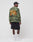 A man faces away, wearing the LIVE FAST DIE YOUNG Copyright Waffle Longsleeve in an oversized camo fit with orange backprint, paired with black cargo shorts, black cap, white socks, and white sneakers against a plain white background.