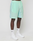 A person wears LIVE FAST DIE YOUNG Beach Shorts in pastel mint green with an elastic waistband, white crew socks featuring LFDY lettering, and white sneakers. The image, cropped above the waist, shows them standing against a plain white background.