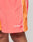 Close-up of a person wearing LIVE FAST DIE YOUNG Beach Shorts in orange and coral with white piping. Features a wide elastic waistband, zippered side pockets, and Live Fast embroidered in white on the left leg.