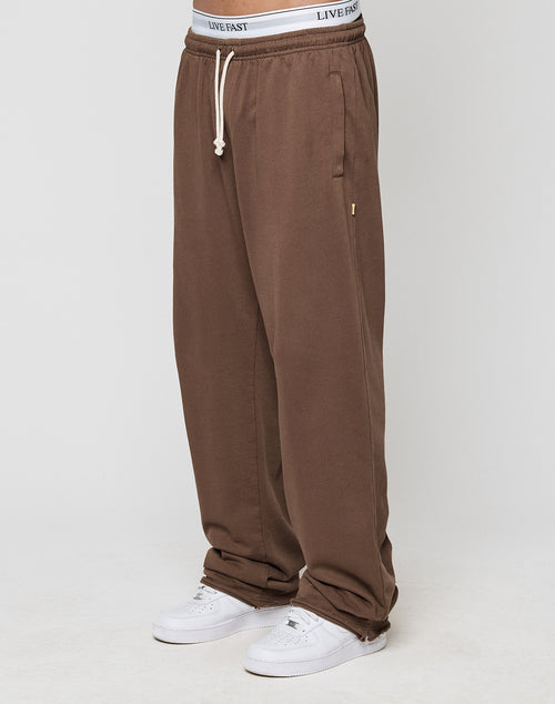 A person wears loose-fitting LFDY Lightweight Jogger sweatpants by LIVE FAST DIE YOUNG, featuring soft French Terry fabric, a drawstring waist, and a visible LIVE FAST waistband, paired with white sneakers against a plain light background.
