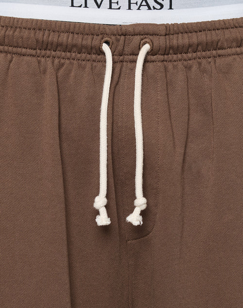 Close-up of the LFDY Lightweight Jogger by LIVE FAST DIE YOUNG in brown, featuring an oversize fit in soft French Terry fabric. White drawstrings and a LIVE FAST-branded underwear waistband are partially visible at the top.