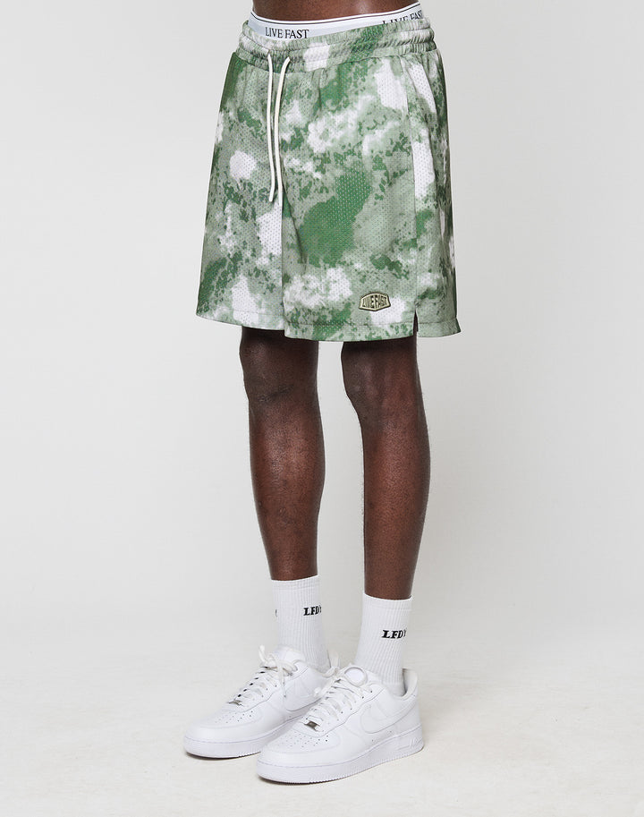 A person wears green and white LFDY Mesh Shorts by LIVE FAST DIE YOUNG (Regular Fit, elastic waistband), white LIVE FAST socks, and white Nike sneakers. Only their legs and lower torso are shown against a plain white background. | model