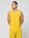 A man models the LIVE FAST DIE YOUNG Live Fast Performance Tank in bright yellow with matching shorts featuring reflective print, standing against a plain light gray background and looking left with his hands behind his back.