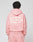 A person with short, twisted hair wears a pink LIVE FAST DIE YOUNG Basic 360 Hooded and matching pants. The hoodie has bold front and back print, sturdy topstitching, and white text. The background is plain.