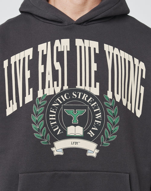 Wearing the LIVE FAST DIE YOUNG Live Fast Die Young Hooded, featuring topstitching, LIVE FAST DIE YOUNG above a crest with an open book, T-shaped emblem, laurel branches, LFDY ribbon, and a vintage effect for authentic streetwear style.