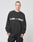 A man with short hair and a neutral expression wears the LIVE FAST DIE YOUNG Live – Fast Sweater, a loose black sweatshirt with bold white LIVE — FAST lettering. The oversize fit and soft cotton-polyester blend offer comfort and style.