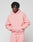 Wearing an oversize fit light pink Basic 360 Hooded sweatshirt and matching sweatpants from LIVE FAST DIE YOUNG, a person stands with hands in the pocket, looking at the camera. The hoodie has topstitching and small LiveFast text on the chest.