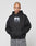 A person with a shaved head, tattoos, and neutral expression wears the LIVE FAST DIE YOUNG LFDY Gambling Hooded—a black oversize 360 GSM hoodie with a bold front photo print—standing against a plain light gray background with hands in the pocket.