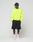 A person in an oversize fit neon yellow Basic Hooded Zip by LIVE FAST DIE YOUNG, black shorts, white socks, white sneakers, and a black baseball cap stands against a plain background, looking to the side with hands in pockets.