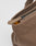 Close-up of the LFDY Tote Bag by LIVE FAST DIE YOUNG: a brown canvas tote with a black zipper partially open, revealing yellow fabric inside. The matching brown pull and dedicated laptop compartment offer secure, stylish storage.