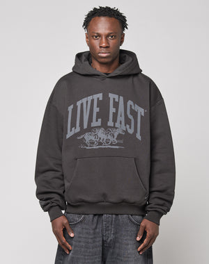 A person wears the LIVE FAST DIE YOUNG Live Fast Stallion Hooded, featuring an oversize fit and bold frontprint, against a plain light background, looking directly at the camera with a neutral expression.