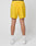 A person is shown from the back against a white background, wearing bright yellow Live Fast Performance Shorts by LIVE FAST DIE YOUNG with Regular Fit, black Elastikbund, and rear pockets, paired with white socks and sneakers.