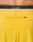 Close-up of the back of bright yellow Live Fast Performance Shorts by LIVE FAST DIE YOUNG, featuring a small zippered pocket and an Elastikbund waistband with black LIVST underwear partially visible above.