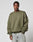 A man stands against a gray background wearing the LFDY Wavy Sweater by LIVE FAST DIE YOUNG, an olive green oversized sweatshirt in soft cotton-polyester blend with subtle seams, light blue jeans, and small white LIVE & FAST text on the chest.