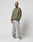A man wearing the LIVE FAST DIE YOUNG LFDY Wavy Sweater in olive green, a light green ribbed beanie, loose faded jeans, and white sneakers stands against a plain white background.