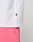Close-up of the lower half of a white LIVE FAST DIE YOUNG Basic OS Livefast Tee (100% Baumwolle) with a small black tag, paired with bright pink shorts. The background is plain and light-colored.