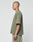 A person with a shaved head and visible tattoos wears the LIVE FAST DIE YOUNG Basic +49 Chest Tee in olive green with beige shorts, standing in profile against a plain light background.