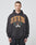 A young man with short hair wears the LIVE FAST DIE YOUNG Live Fast Die Young Hooded, a black hoodie with bold orange “LIVE FAST DIE YOUNG” lettering and laurel graphic, made from soft Baumwolle Polyester, standing before a plain light gray background.