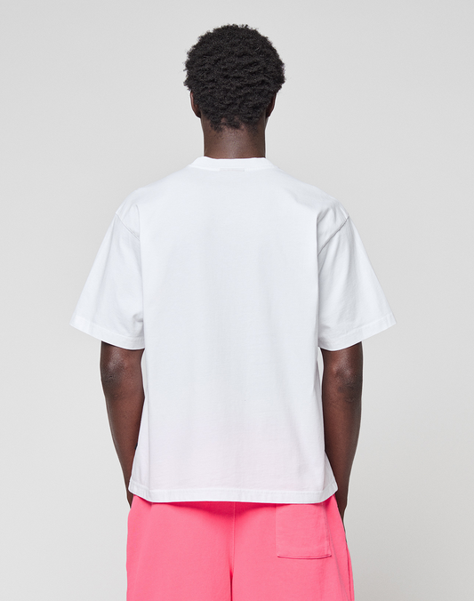 A person faces away from the camera, wearing a LIVE FAST DIE YOUNG Basic OS Livefast Tee in plain white and bright pink shorts with a back pocket, set against a neutral gray background.