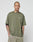 A person with a shaved head and tattoos wears the olive green LIVE FAST DIE YOUNG Basic +49 Chest Tee, made from 100% Baumwolle, and light shorts, standing against a white background with hands in pockets.