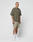 A tattooed person wears the LIVE FAST DIE YOUNG Basic +49 Chest Tee in olive green with matching shorts, white crew socks, and white sneakers, standing calmly against a plain white background.