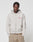A man with braided hair models the LFDY Corp. Hooded Zip by LIVE FAST DIE YOUNG, an oversized 100% Baumwolle hoodie in light beige with a red and white chest graphic, posing with hands in pockets against a white background.