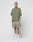 A man with short hair and visible tattoos wears an oversized olive green t-shirt and LIVE FAST DIE YOUNG Basic Mesh Shorts in olive green with elastic waistband, paired with white crew socks and sneakers. He stands against a plain white background, hands in his pockets.