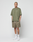 A person stands against a plain white background wearing an olive green oversized t-shirt, LIVE FAST DIE YOUNG Basic Mesh Shorts in olive with an elastic waistband and subtle logo patch, white crew socks, and white sneakers for a casual look.