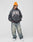 A man in an orange beanie, loose faded jeans, and white sneakers stands against a light gray background wearing an oversized dark gray LIVE FAST DIE YOUNG Live Fast Axe Hooded with his hands in the hoodie pocket.