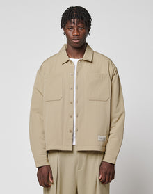 A man with short, textured hair wears the LIVE FAST DIE YOUNG LFDY Padded Shirt over a white top and matching beige pants, standing against a plain light gray background.