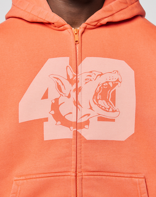 A close-up of the orange LFDY 40 Hooded Zip by LIVE FAST DIE YOUNG, crafted from Baumwolle Pullover material and featuring a bold front print of the number 49 with a spiked-collar dog's head, mouth open.