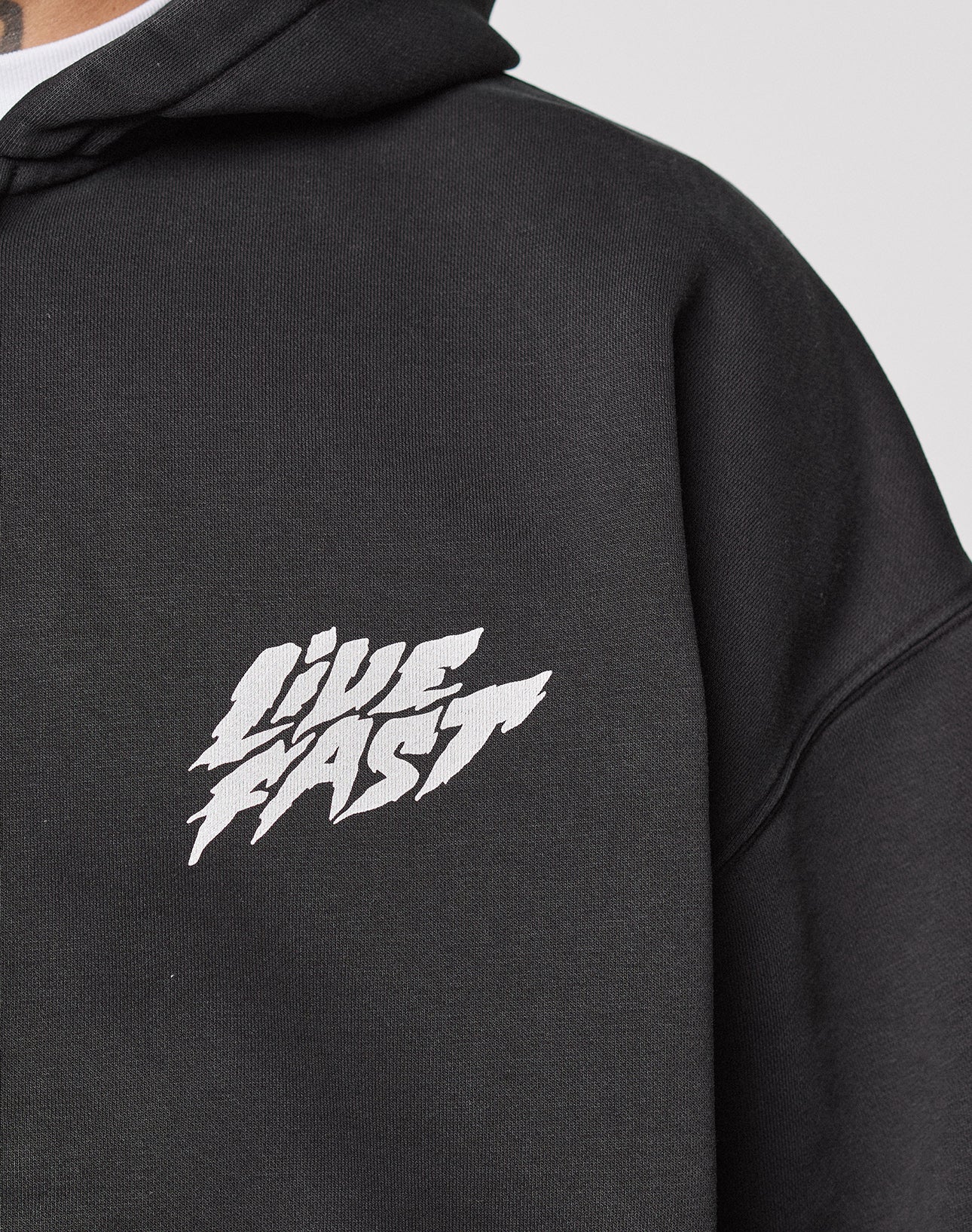 Close-up of the LFDY Logo Hooded Zip by LIVE FAST DIE YOUNG, a black oversized cotton hoodie with bold, stylized white "LIVE FAST" text across the chest.