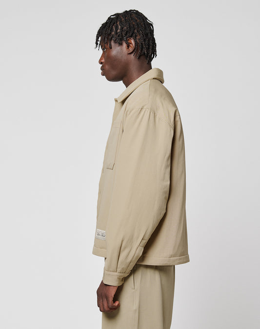 A person with short, curly hair stands in profile against a plain white background, wearing the LIVE FAST DIE YOUNG LFDY Padded Shirt in light beige oversize fit with matching pants and visible chest pockets.