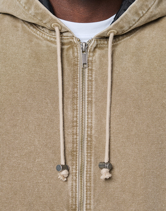 Close-up of a person wearing the LIVE FAST DIE YOUNG Faded Workwear Jacket, a beige zip-up hoodie with cream drawstrings and metal tips, styled over a white shirt. Only the lower face and upper chest are visible.