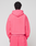 A person faces away from the camera, wearing a bright pink LIVE FAST DIE YOUNG Basic Hooded Zip oversize hoodie and matching sweatpants with a pocket, set against a plain light background.