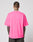 A person with short hair and visible tattoos on their neck and arms is shown from the back, wearing the bright pink LFDY Triple Racing Tee by LIVE FAST DIE YOUNG, styled with dark pants against a plain light background.