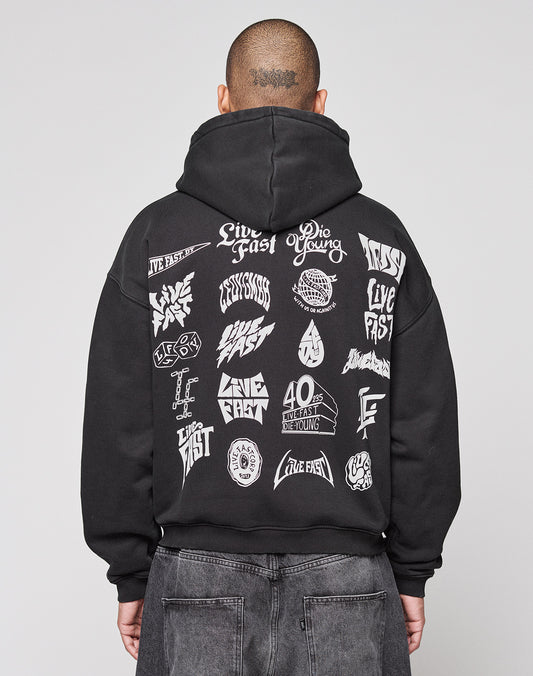 A person faces away from the camera in a black LIVE FAST DIE YOUNG LFDY Logo Hooded Zip, an oversized Baumwolle hoodie with multilogo white graphics and “Live Fast” and “Die Young” phrases on the back, set against a plain gray background.