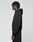 A person stands in profile against a plain light background, wearing the LIVE FAST DIE YOUNG Basic Hooded Zip and matching black pants. Their hair is styled in short twists, and their hands rest relaxed at their sides.