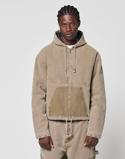 A person with braided hair wears a tan Faded Workwear Jacket by LIVE FAST DIE YOUNG with a hood, drawstrings, and a kangaroo pocket, paired with matching pants against a plain light gray background.